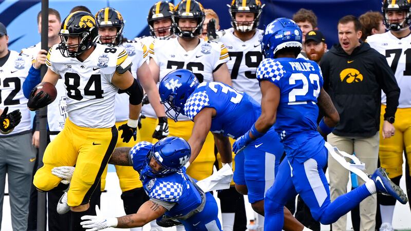 Iowa tight end Sam LaPorta (84) carries the ball after catching a pass as Kentucky defenders...