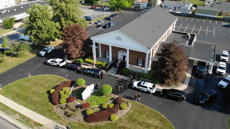 The hearse carrying Toledo Police Officer Anthony Dia prepares to leave the funeral home...