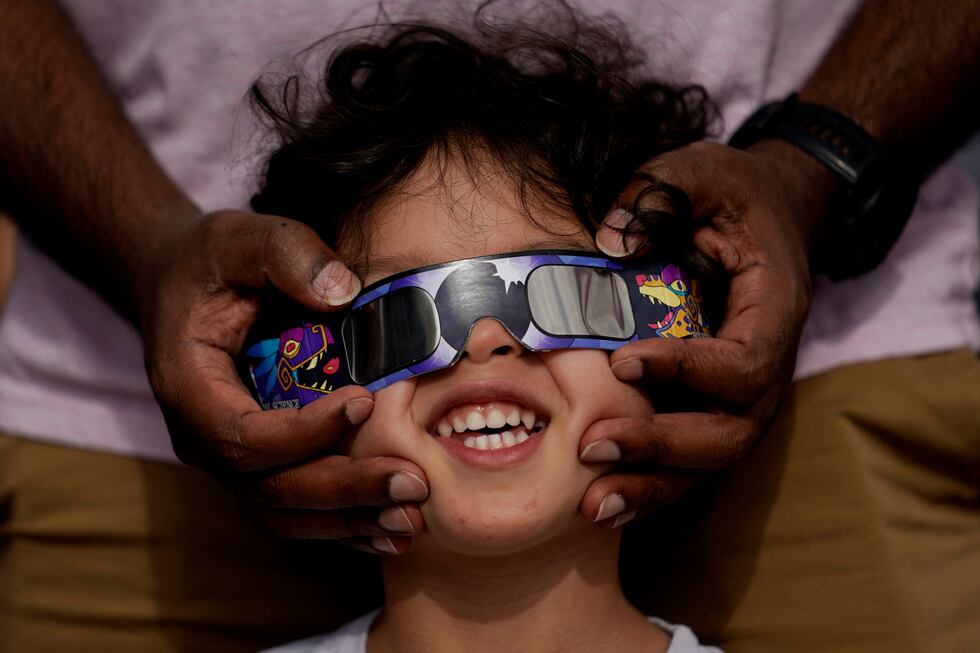 Viewers use special glasses to watch from San Antonio, as the moon moves in front of the sun...