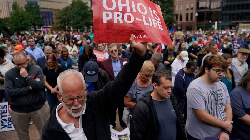 Paul Meacham holds high a sign that reads "Ohio is pro-life" as the crowd prays during the...